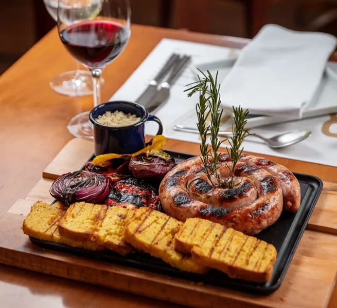 Linguiça artesanal grelhada com polenta e legumes no ¡Vení! Parrilla